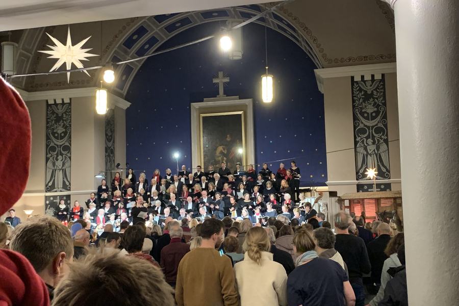 Voll besetzte Hoffnungskirche bei einem Konzert, vorn der Chor vor dem blauen Sternenhimmel des Altarraums